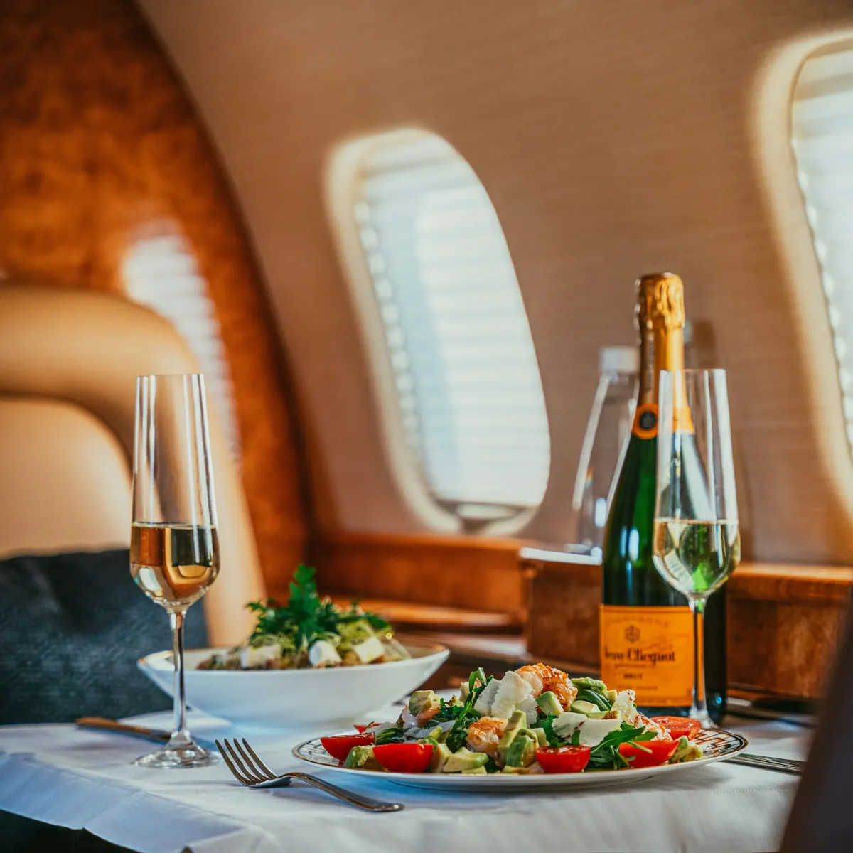 Dining table set with salad and champagne beside a cabin window