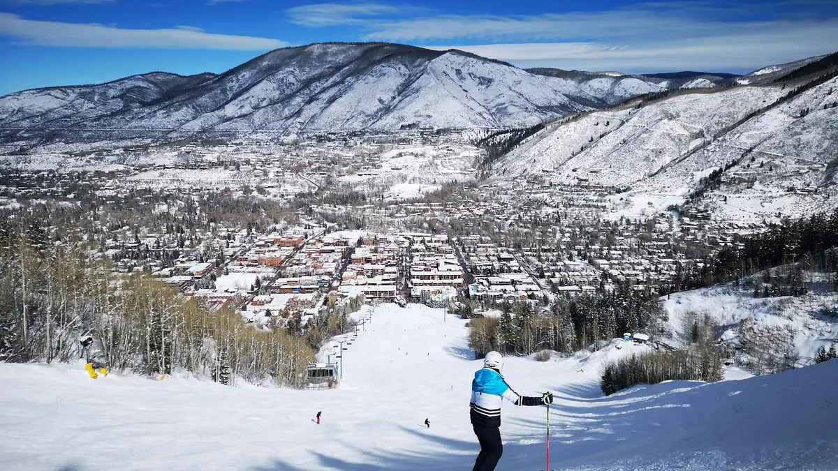 Skier on a groomed run above Aspen with mountains behind