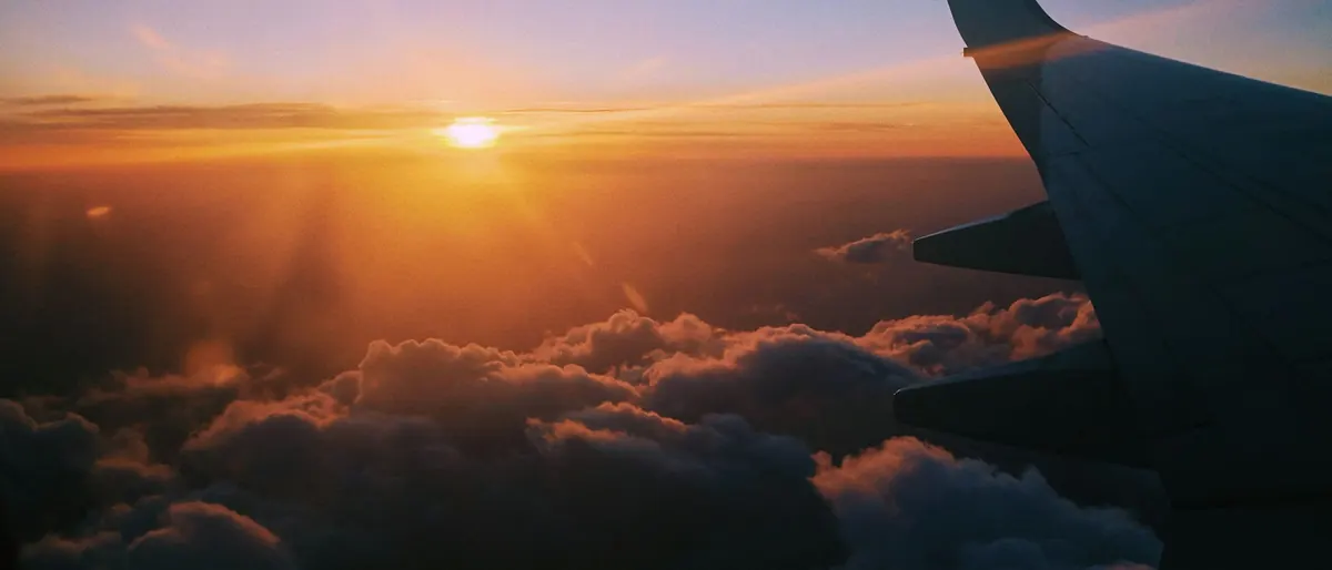 Aircraft wing above a sea of clouds at sunset